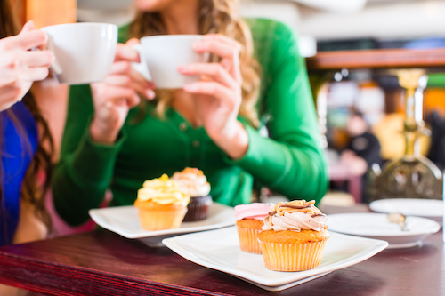 Friends having fun and eating muffins at bakery or pastry shop 