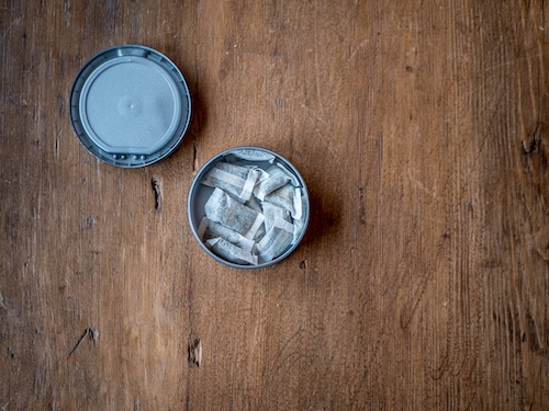 Swedish Nicotine. White Portion Snus in round container on wood table.